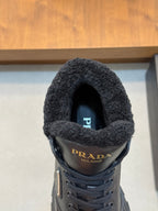 Front close-up of Prada dark leather sneaker showing shearling-lined collar and logo badge