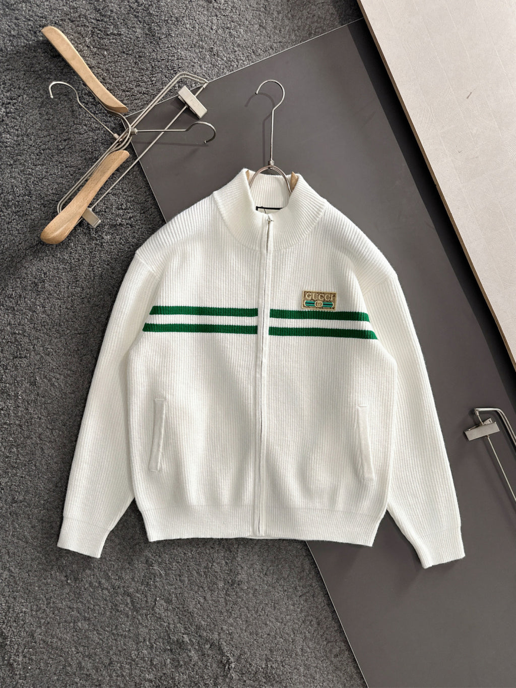White zip knit sweater with green stripe band and logo patch