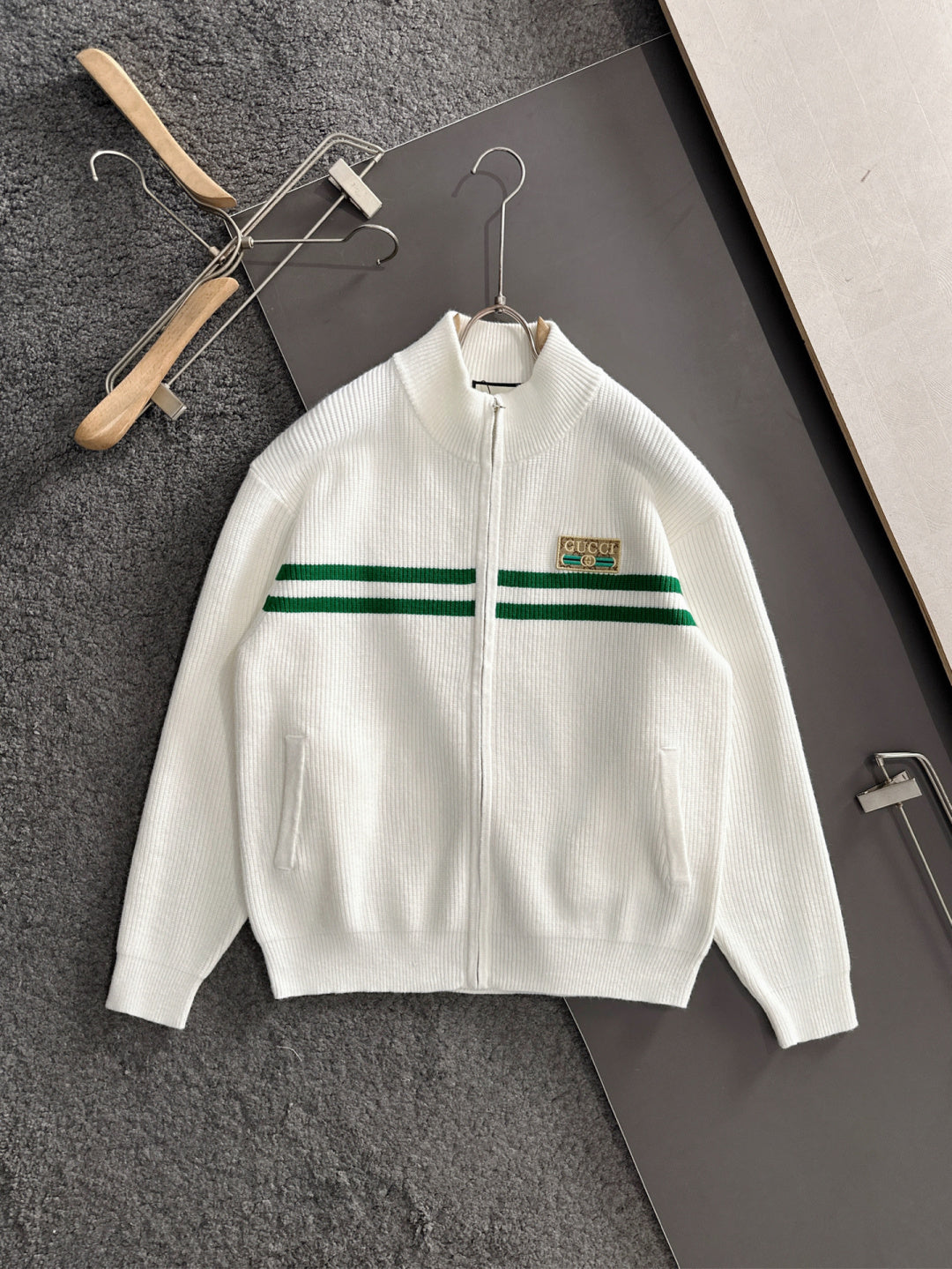 White zip knit sweater with green stripe band and logo patch