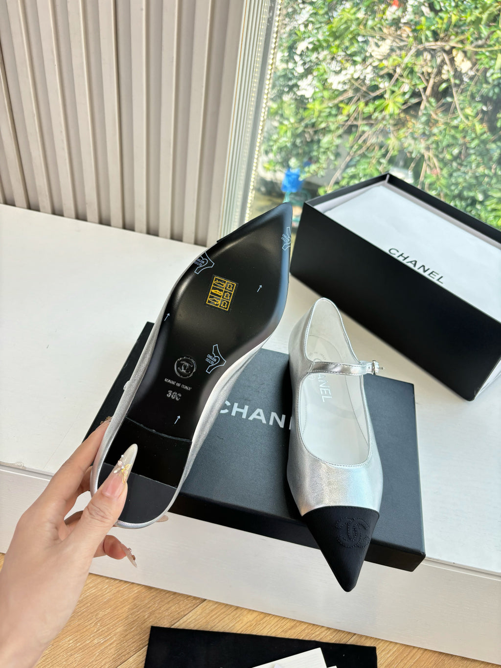 Women’s Chanel flats showing printed insole, silver upper with black toe cap
