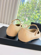 Two-tone flats with beige upper, black sole, and top handle strap with logo