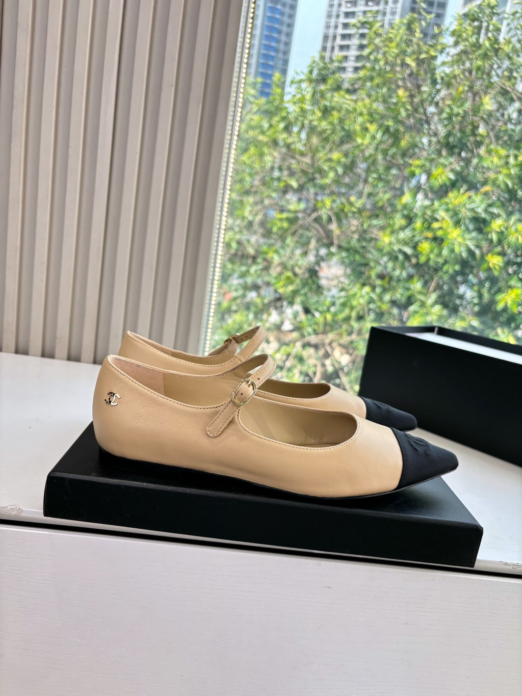 Beige pointed-toe flats with ankle strap and small bow detail on the upper