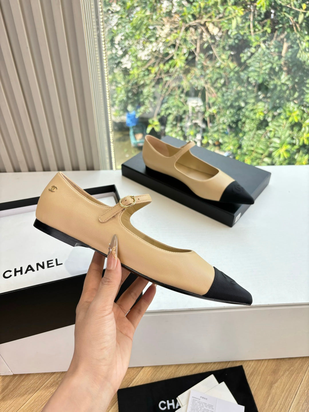 Beige pointed-toe flats with black toe sections and a thin ankle strap