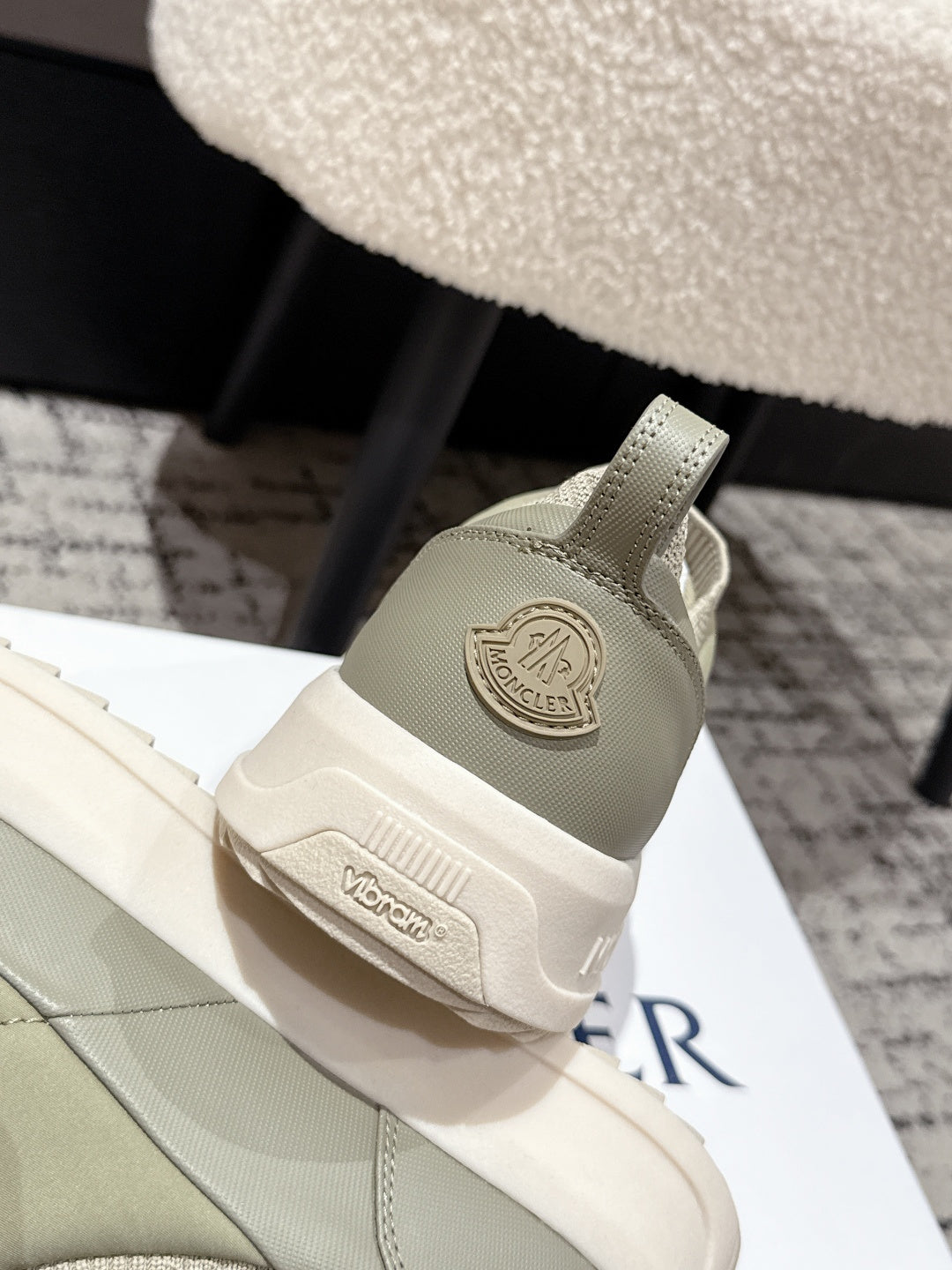 Moncler slip-on shoe heel detail in light olive with circular logo patch.