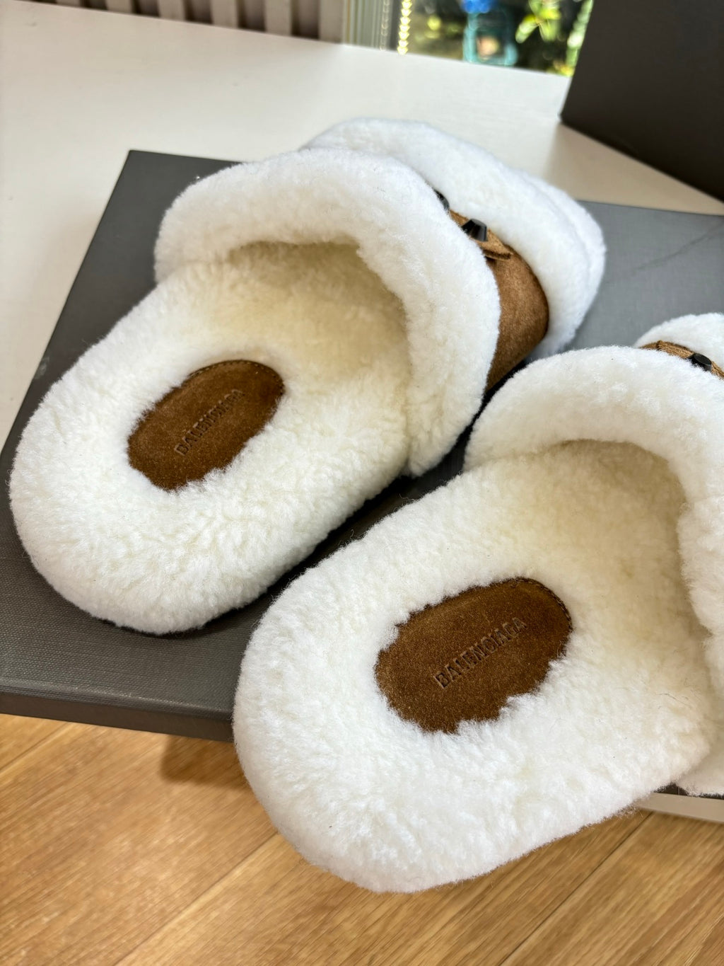 Balenciaga shearling slide sandals, close-up white plush footbed with brown logo patch