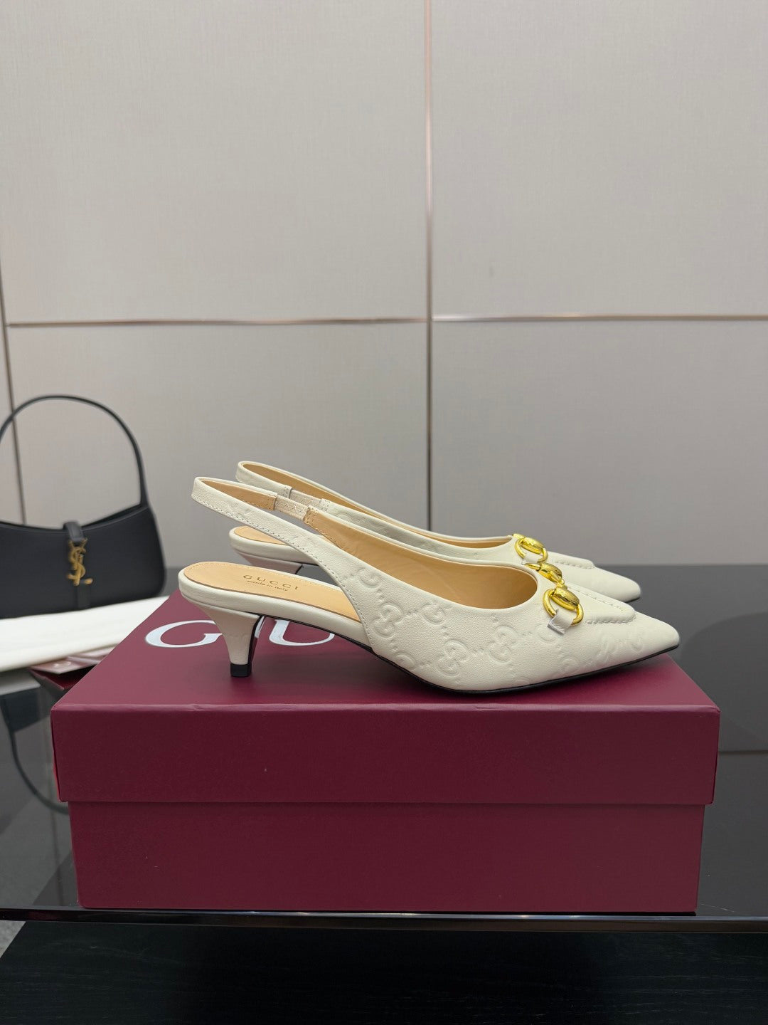 Cream slingback pumps with embossed logo pattern and gold horsebit