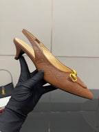 Brown slingback heel held in hand with gold ring detail and pointed toe