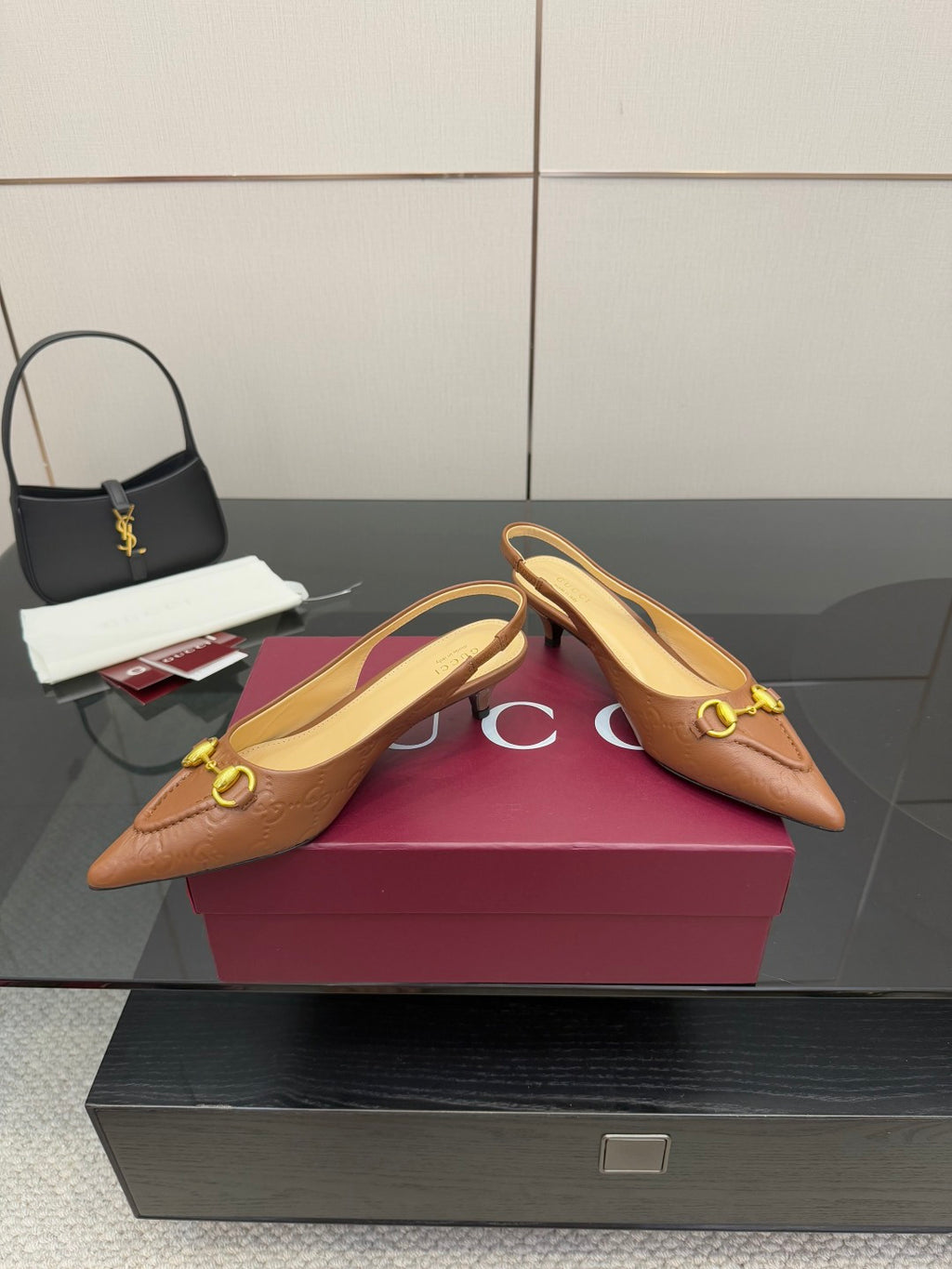 Brown slingback heels displayed on box, gold hardware and pointed toe