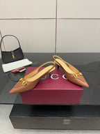 Brown slingback heels displayed on box, gold hardware and pointed toe
