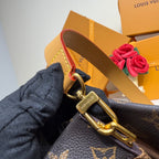 Louis Vuitton tote bag close-up with tan web strap, gold hardware, and textured monogram canvas.