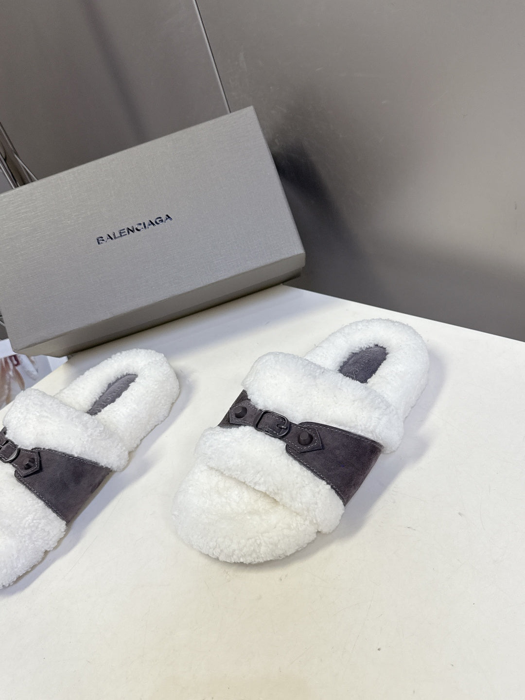 Pair of faux shearling slide sandals with dark buckled strap, white