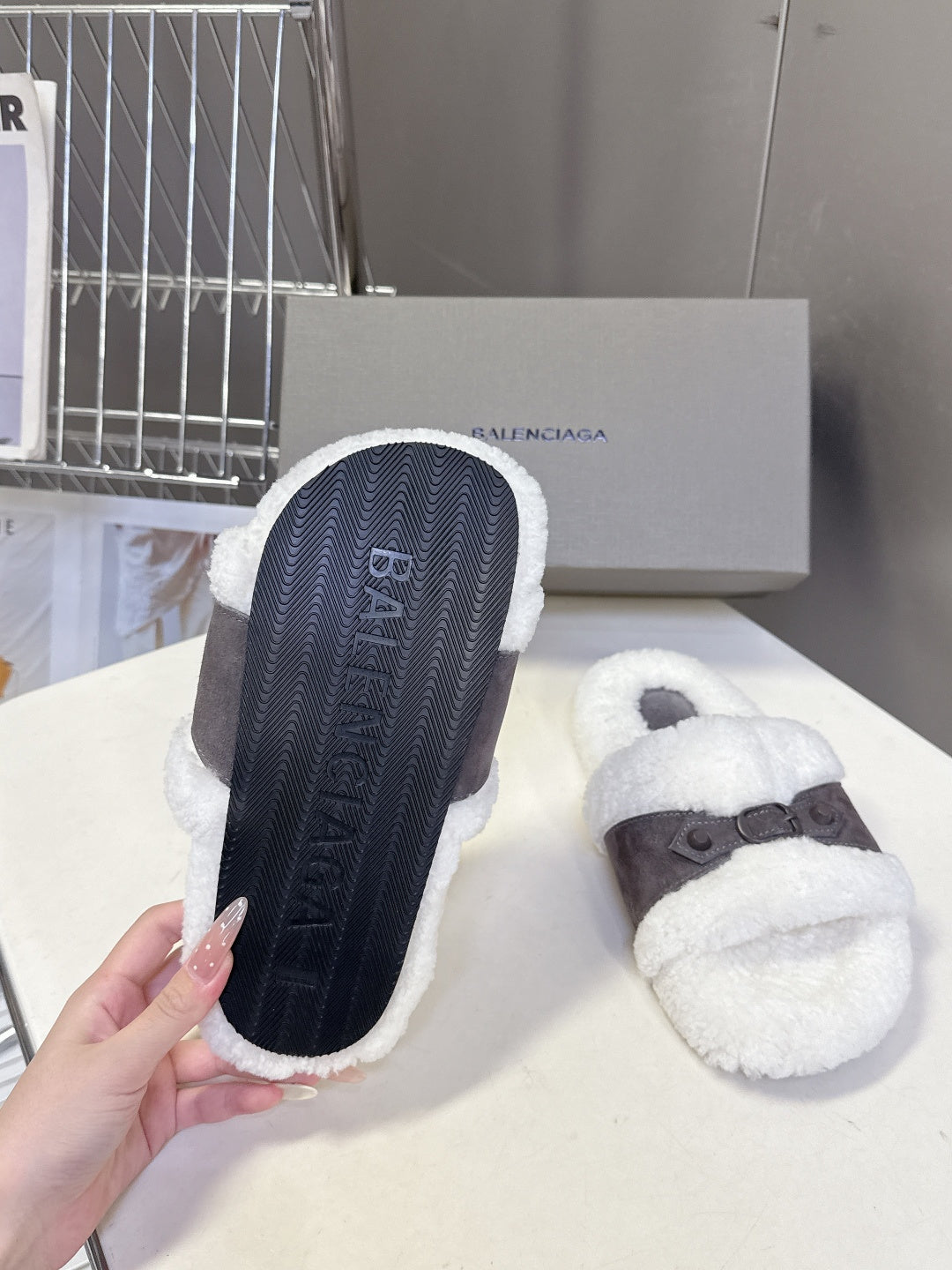 Faux shearling slide sandals showing textured navy outsoles and dark straps, white