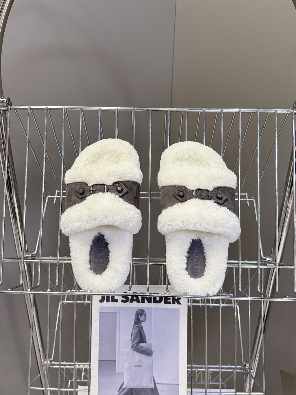 Pair of white faux shearling slide sandals with dark buckled straps