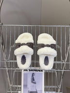 Pair of white faux shearling slide sandals with dark buckled straps