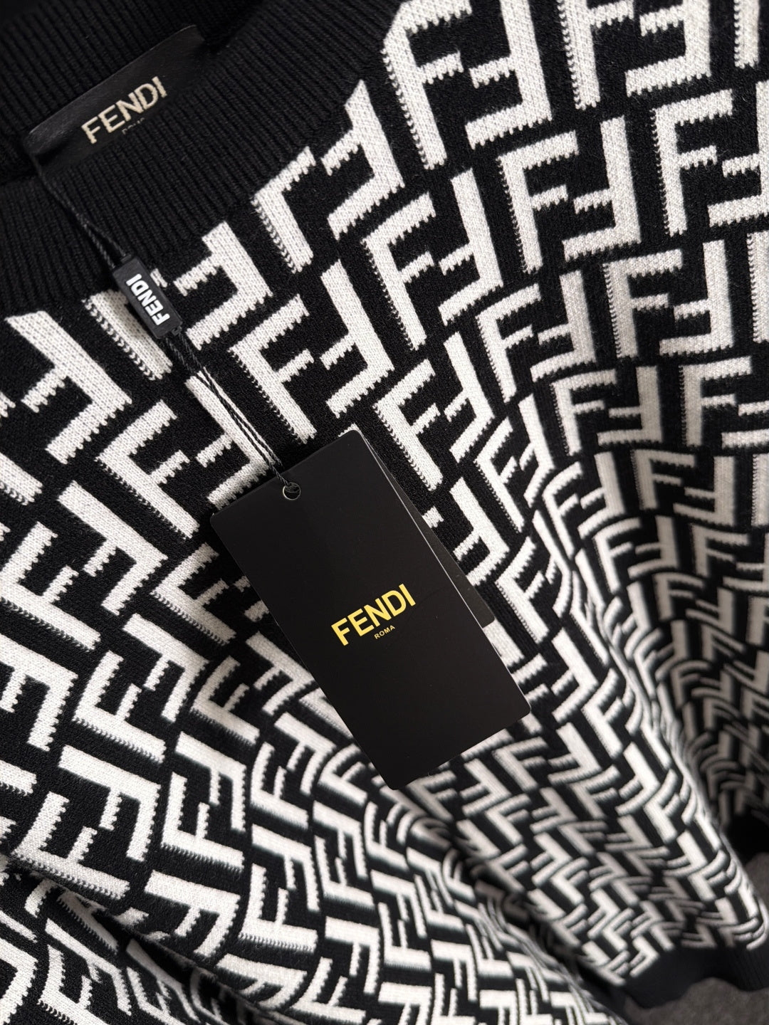 Fendi long-sleeve knit top front close-up, black with white FF logo and tag
