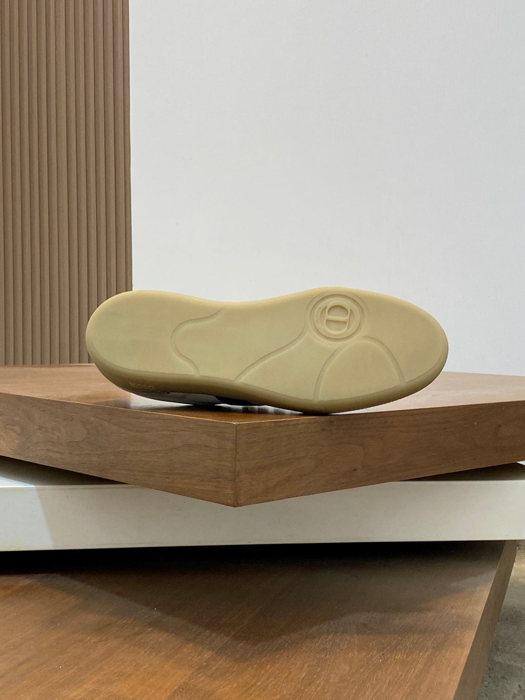 Low-top sneaker outsole in light tan rubber with tread and circular logo mark