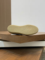 Low-top sneaker outsole in light tan rubber with tread and circular logo mark