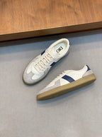 Pair of low-top sneakers with white upper, blue stripe, and tan gum outsole