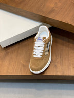 Tan suede low-top sneakers with white laces and blue-and-white plaid side patch