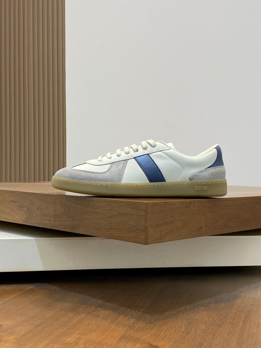 Low-top sneakers with white upper, blue stripe panel, and tan rubber sole