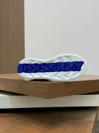 Sneaker outsole with white tread and blue branding on the heel area