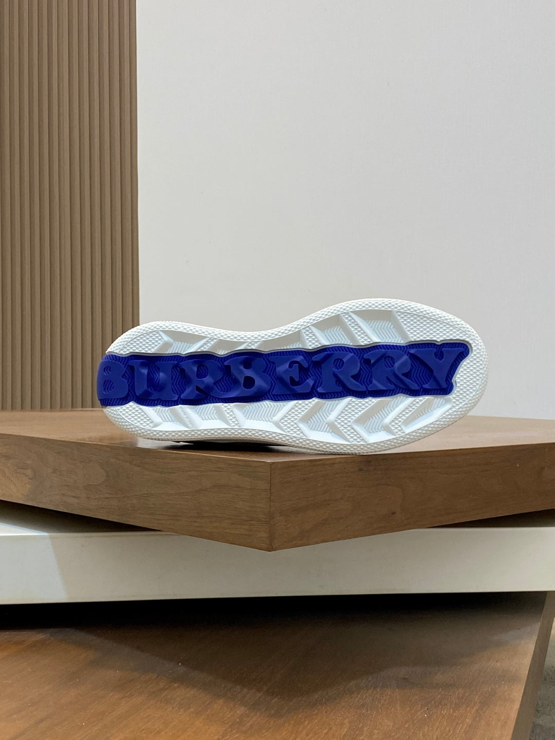 Sneaker outsole with white tread and blue branding on the heel area