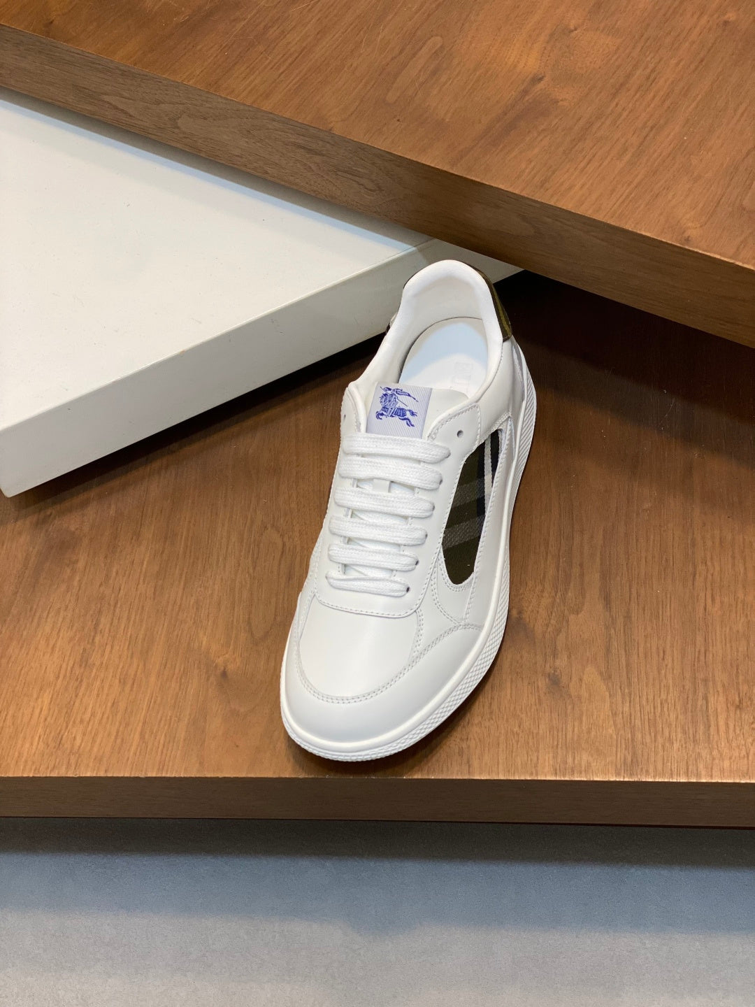 White lace-up sneaker with plaid side panel and low rubber sole.