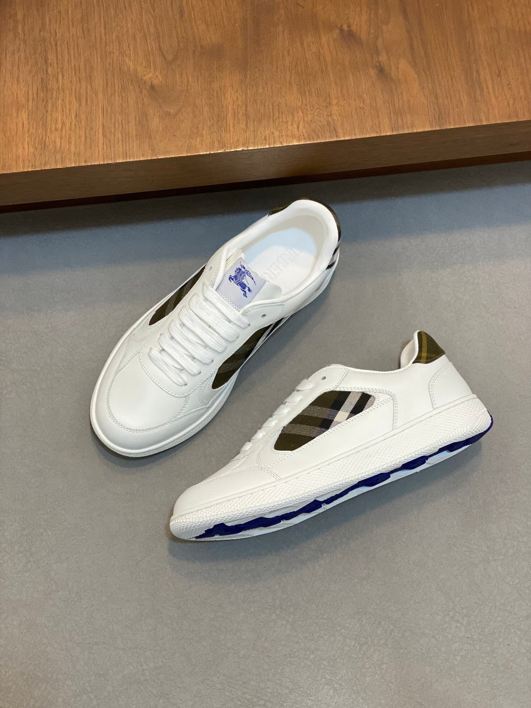 White sneakers with plaid side panel and textured rubber sole with blue edge.