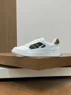 White sneakers with black plaid side insets and blue-striped rubber sole.