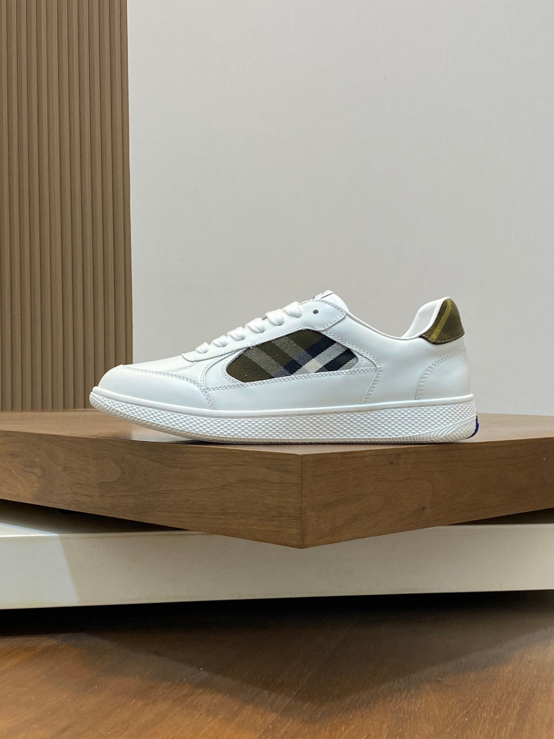 White sneakers with black plaid side insets and blue-striped rubber sole.
