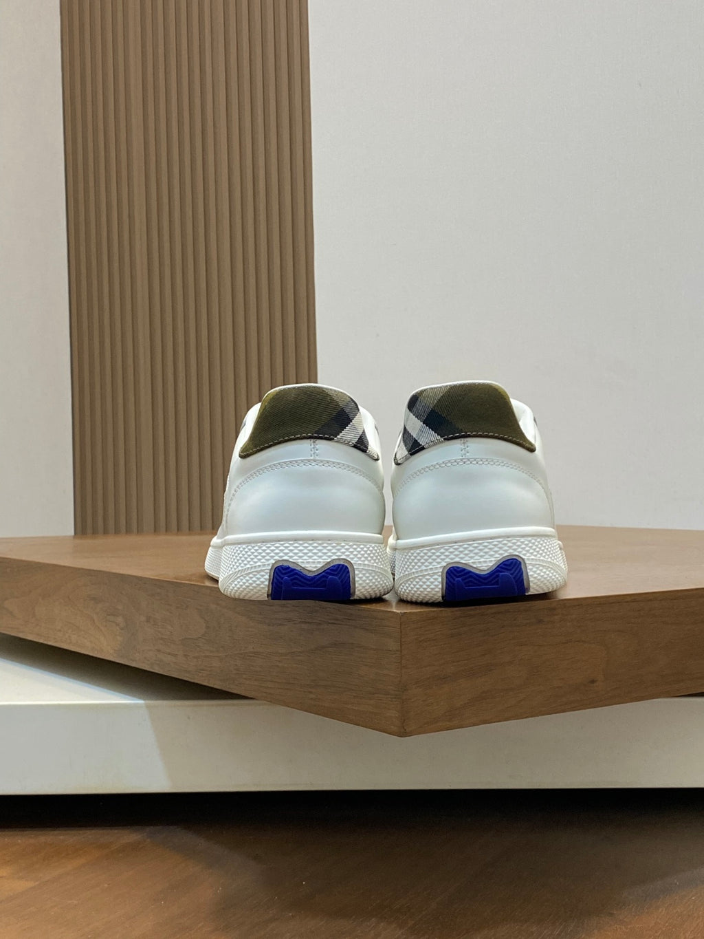 Pair of white sneakers with blue tread and plaid heel accents.