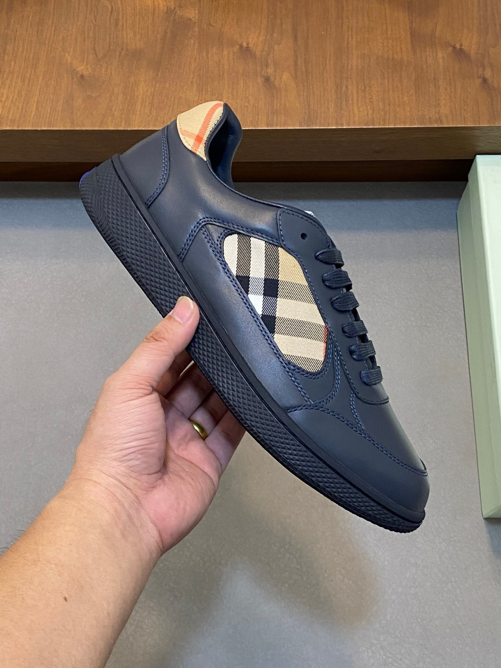 Burberry low-top sneaker held by hand, blue leather with check insert