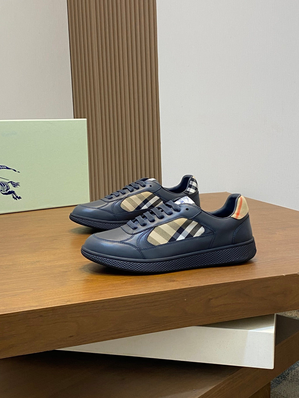 Burberry low-top sneakers on display platform, blue upper with beige check detail