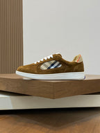 Brown suede low-top sneaker side view with blue-and-white check patch and white rubber sole