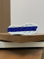 White sneaker outsole with blue Burberry lettering and textured tread.
