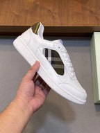 White leather sneaker with lace-up front and plaid side panel, held in hand.