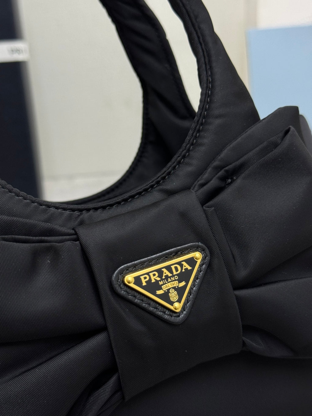 Prada black nylon mini bag front with bow and gold Prada logo triangle