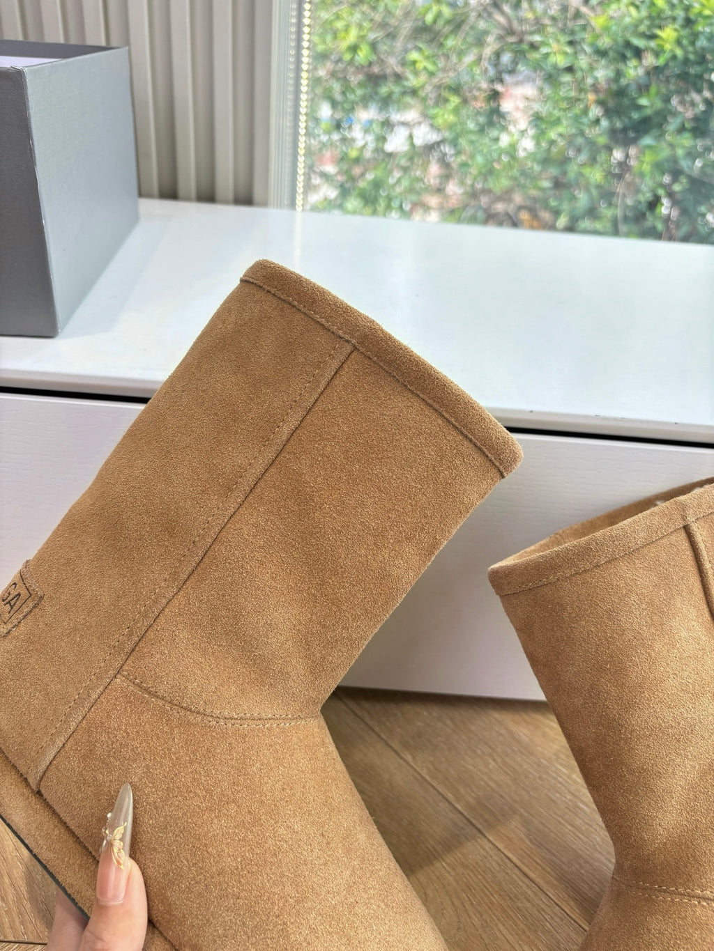 Tan suede mid-calf boot with stitched seams and shearling-lined cuff