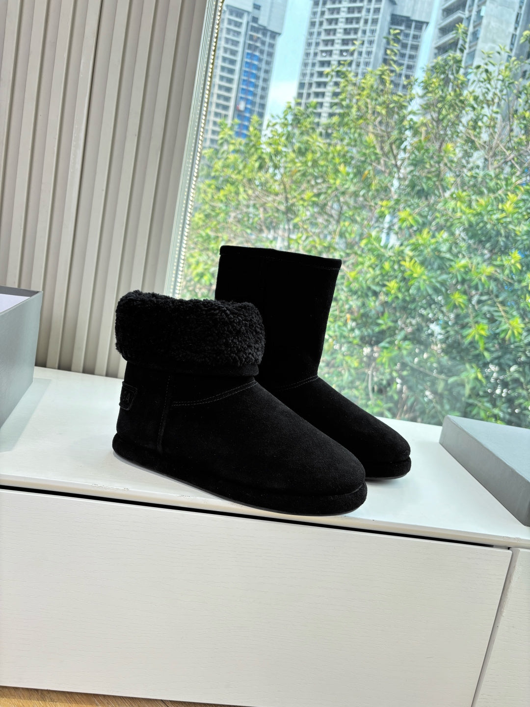 Black suede ankle boots with fuzzy top, single pair on display