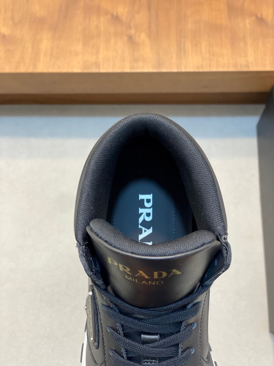 Prada sneaker tongue close-up in dark fabric with logo branding.