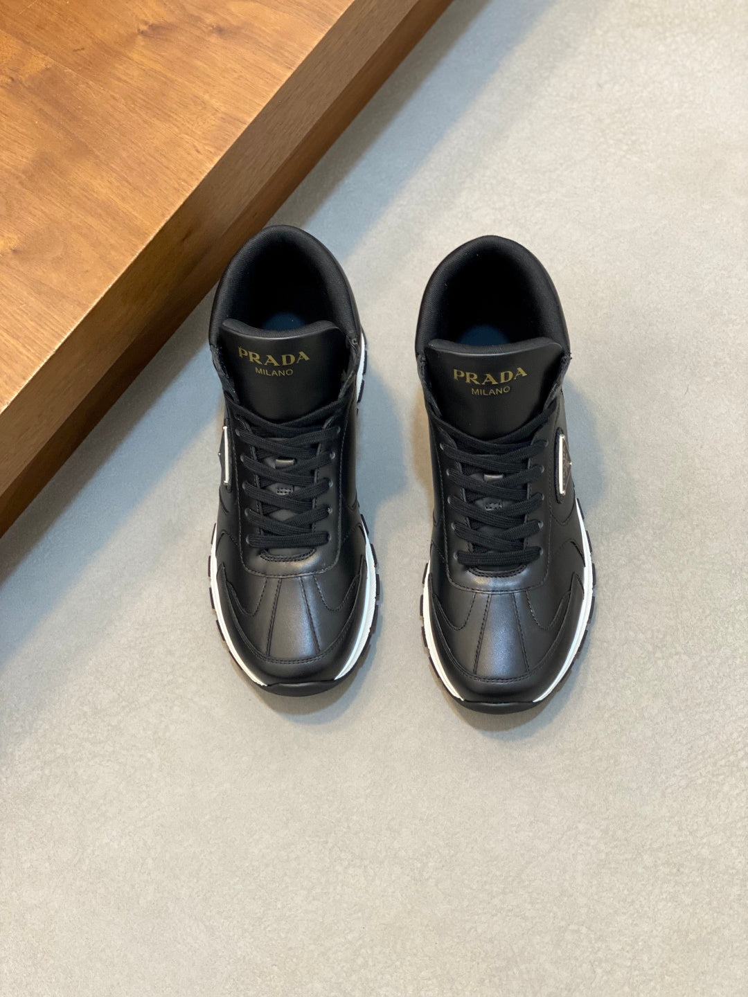 Prada sneakers in dark leather, lace-up with side logo, low-profile sole.