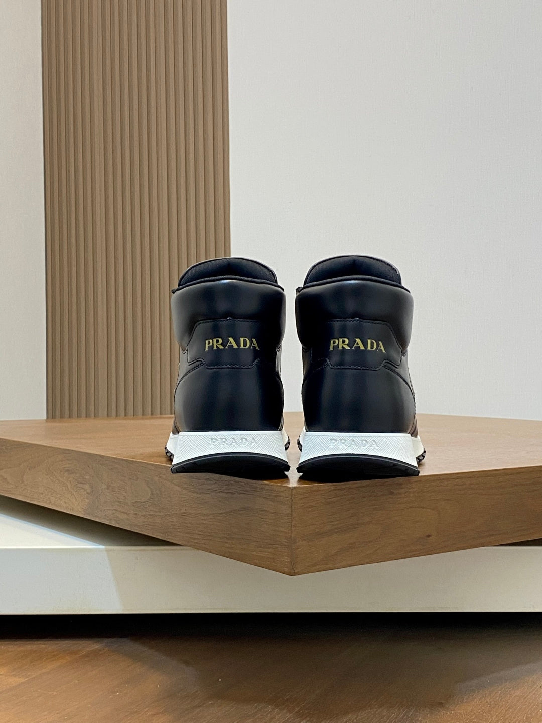 Prada sneakers from the back, dark uppers with heel branding.