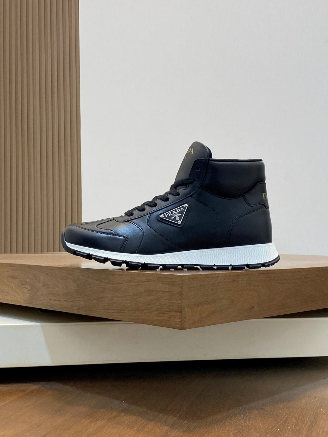 Prada dark leather sneakers, side view with lace-up and logo on upper.
