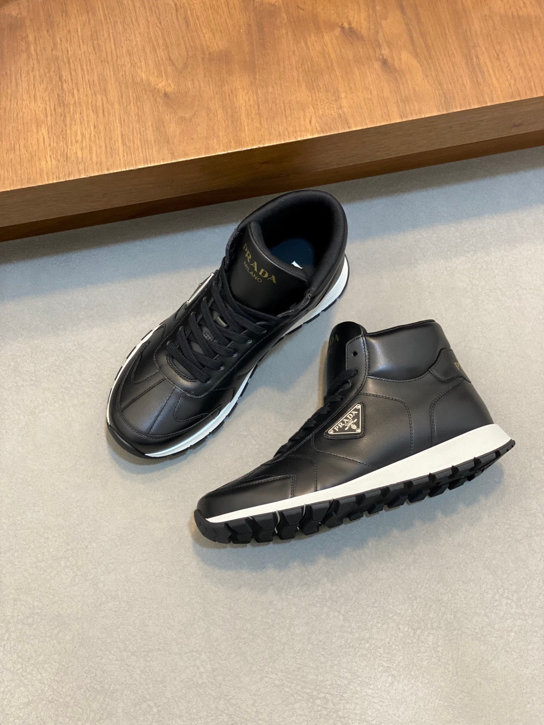 Prada dark leather sneakers, one shoe side view with textured sole tread.