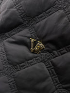 Versace quilted jacket fabric detail with gold crest emblem on chest pocket
