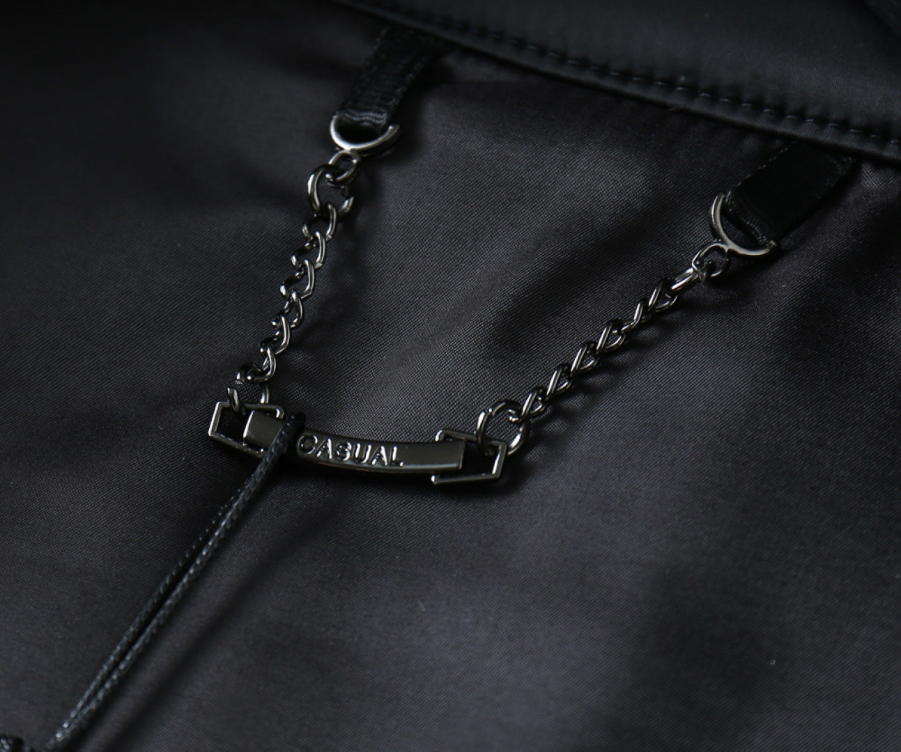 Black jacket fabric with silver-tone chain and rectangular logo tag