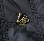 Black quilted jacket emblem patch detail with gold-toned logo