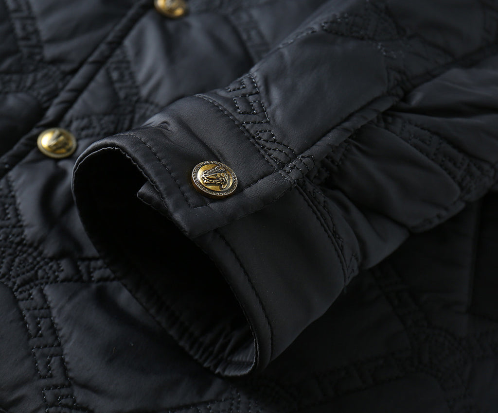 Black quilted jacket cuff with snap buttons and gold logo emblem