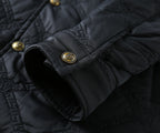 Black quilted jacket cuff with snap buttons and gold logo emblem
