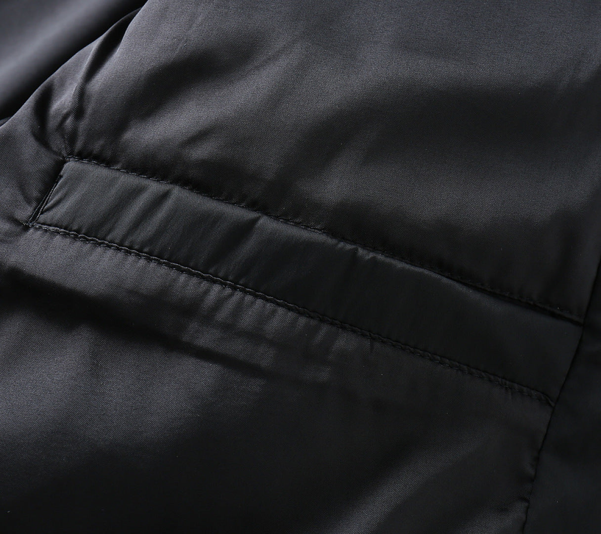 Black jacket lining close-up with horizontal seam and smooth fabric panel